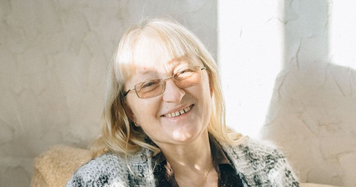 A smiling older woman in a knit cardigan